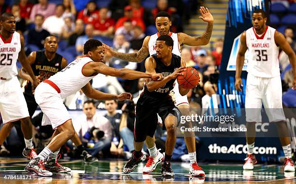 Devon Bookert of the Florida State Seminoles tries to keep the ball away from Nick Faust and teammate Roddy Peters of the Maryland Terrapins during...