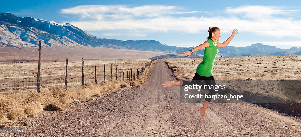 Woman leaping across dirt road