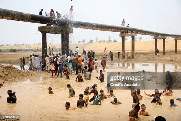 Pakistani people cool off at water supply pipelines during a heatwave in Karachi, Pakistan on June 25, 2015. More than 1,000 people have been killed...