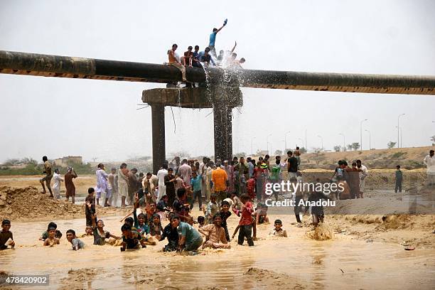 Pakistani people cool off at water supply pipelines during a heatwave in Karachi, Pakistan on June 25, 2015. More than 1,000 people have been killed...