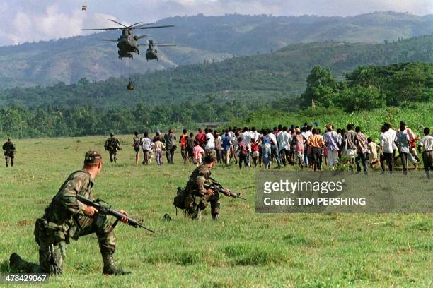 Hundreds of local residents run towards US Shinook helicopters, on September 24 as a detachment of over 100 US troops arrive in this small southern...