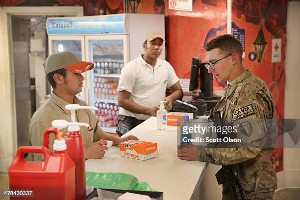 Jonathan Shaw orders chicken from a Popeyes Louisiana Kitchen restaurant in the post exchange complex on Bagram Airfield on March 13, 2014 near...