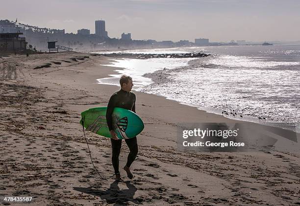 Surfer heads out into the ocean at Will Rogers State Beach on March 3 in Santa Monica Beach, California. Millions of tourists flock to the Los...