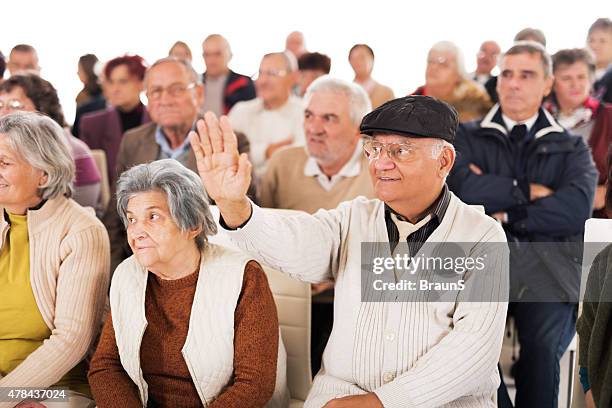 smiling senior man raising his hand on education event. - community college stockfoto's en -beelden