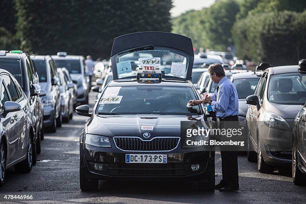 Taxi driver cleans his windscreen as French cab drivers sit parked during a protest against Uber Technologies Inc.'s car sharing service in Paris,...