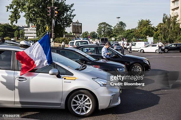 The French national flag flies from the drivers window of a Toyota Yaris Hybrid automobile as French cab drivers block traffic at Porte Maillot...