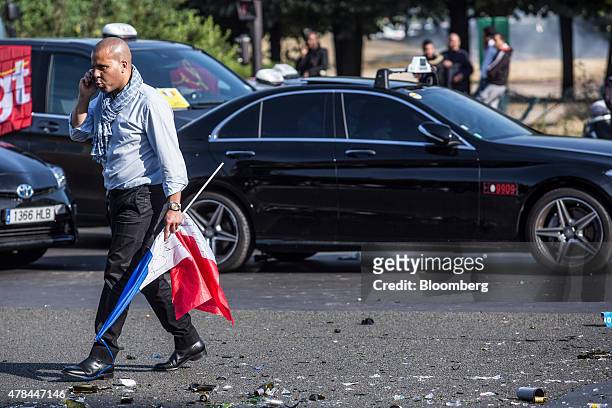 Taxi diver speaks on a mobile phone as he carries a French national flag while cab drivers protest against Uber Technologies Inc.'s car sharing...