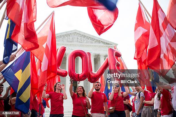 Marriage equality supporters hold up "LOVE" balloons outside the Supreme Court as they walk down an aisle lined with equality flags as they wait for...