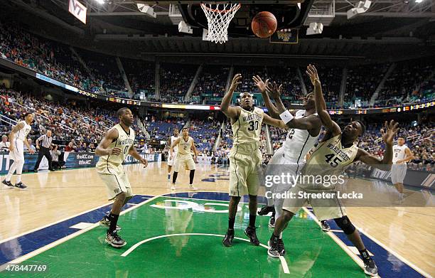 Teammates Travis McKie and Arnaud William Adala Moto of the Wake Forest Demon Deacons battle for a rebound against Talib Zanna of the Pittsburgh...