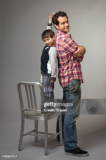 son measuring height next to father - kids standing crossed arms stock-fotos und bilder