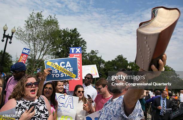 Protester waves his bible in the air as he overpowered by cheers from supporters of the Affordable Care Act as they celebrate the opinion for health...