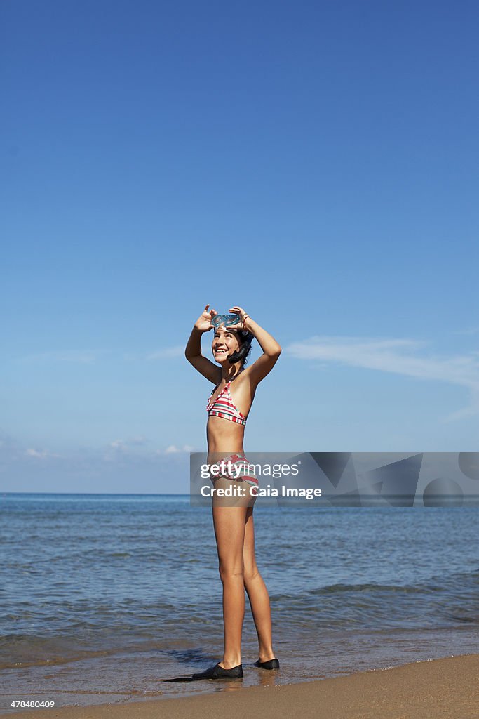 Smiling girl wearing goggles and flippers on beach