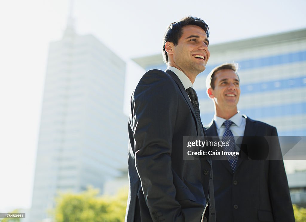 Smiling businessmen in front of highrise