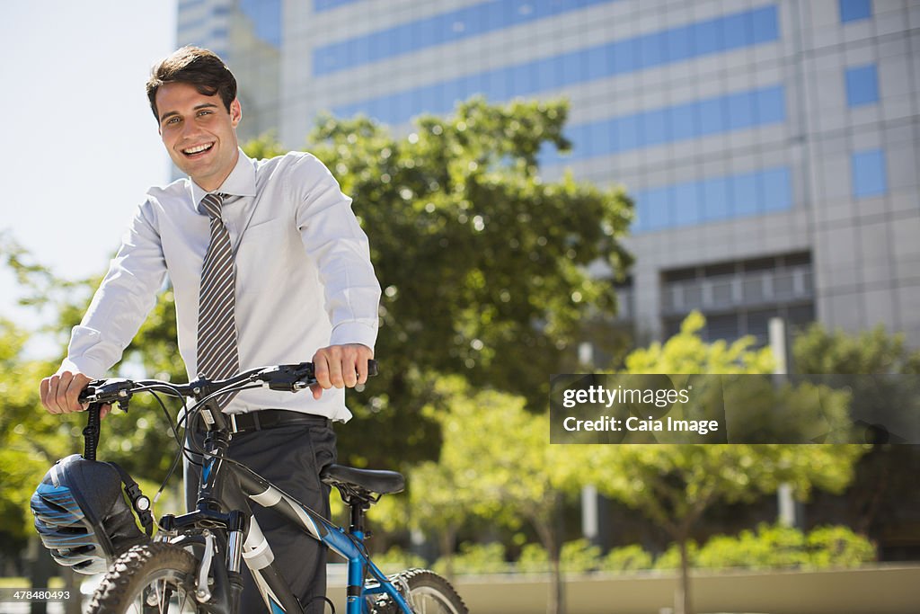 Smiling businessman with bicycle outdoors