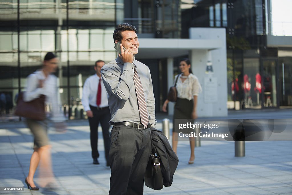 Smiling businessman talking on cell phone outside urban building