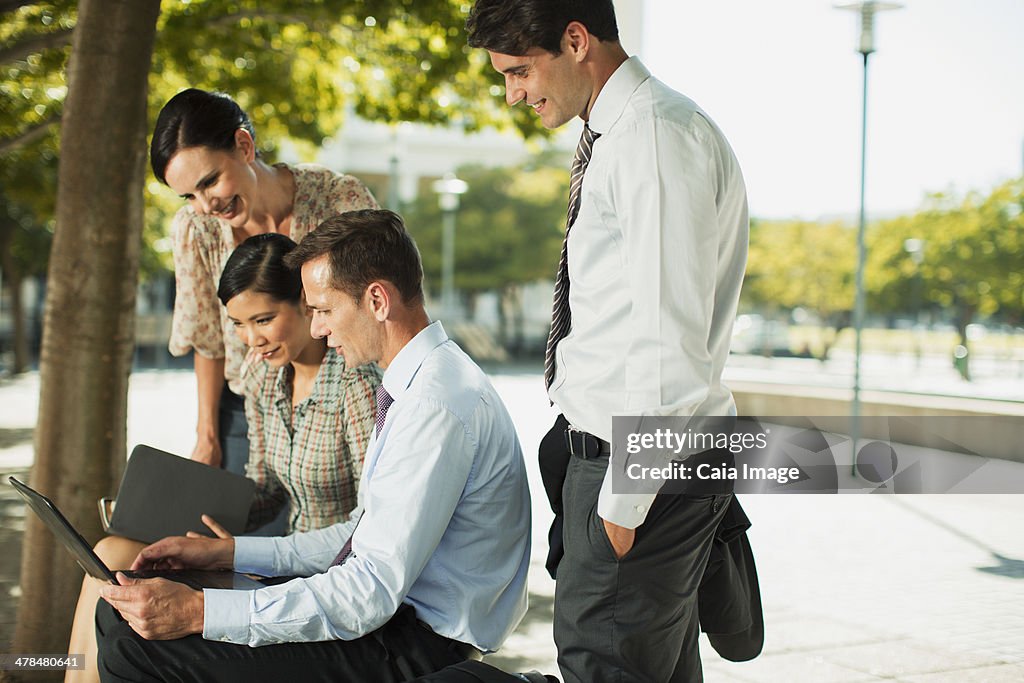 Business people using laptop in urban park