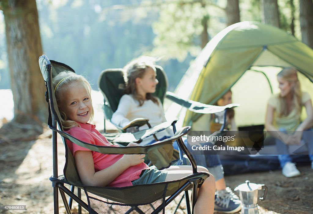 Smiling girl sitting in chair at campsite