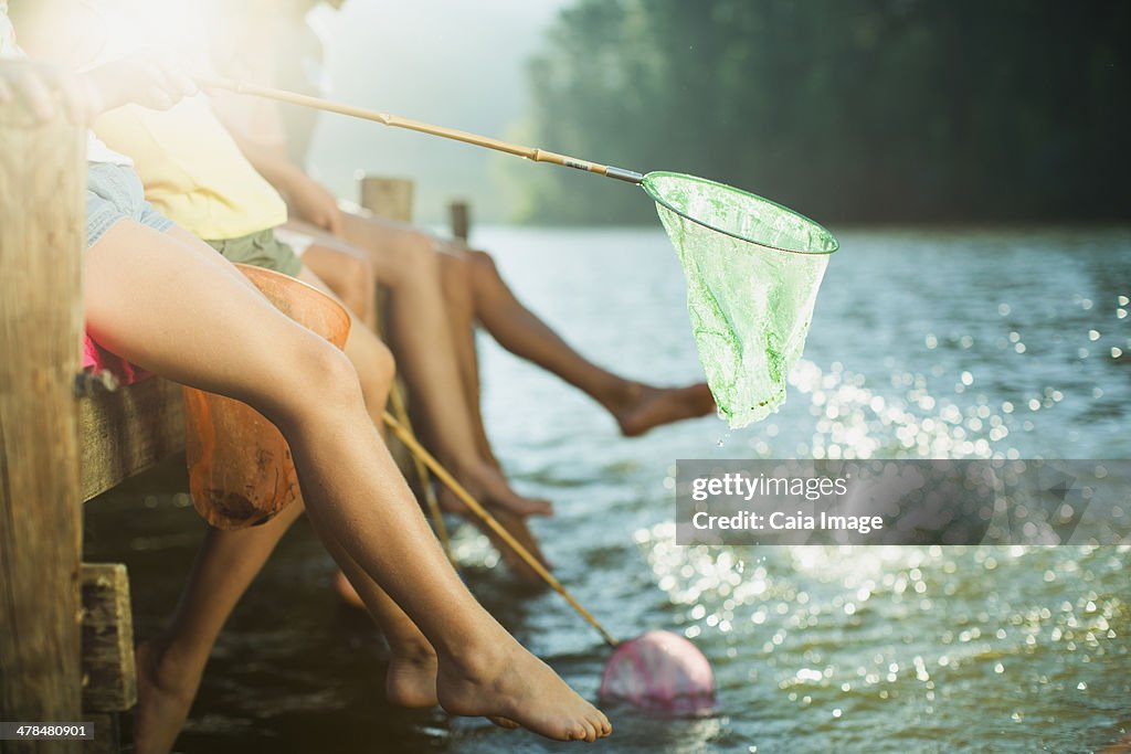 Family on dock with fishing nets dipping feet in lake