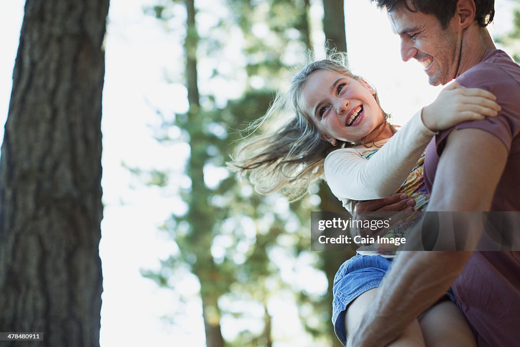 Father spinning daughter in woods