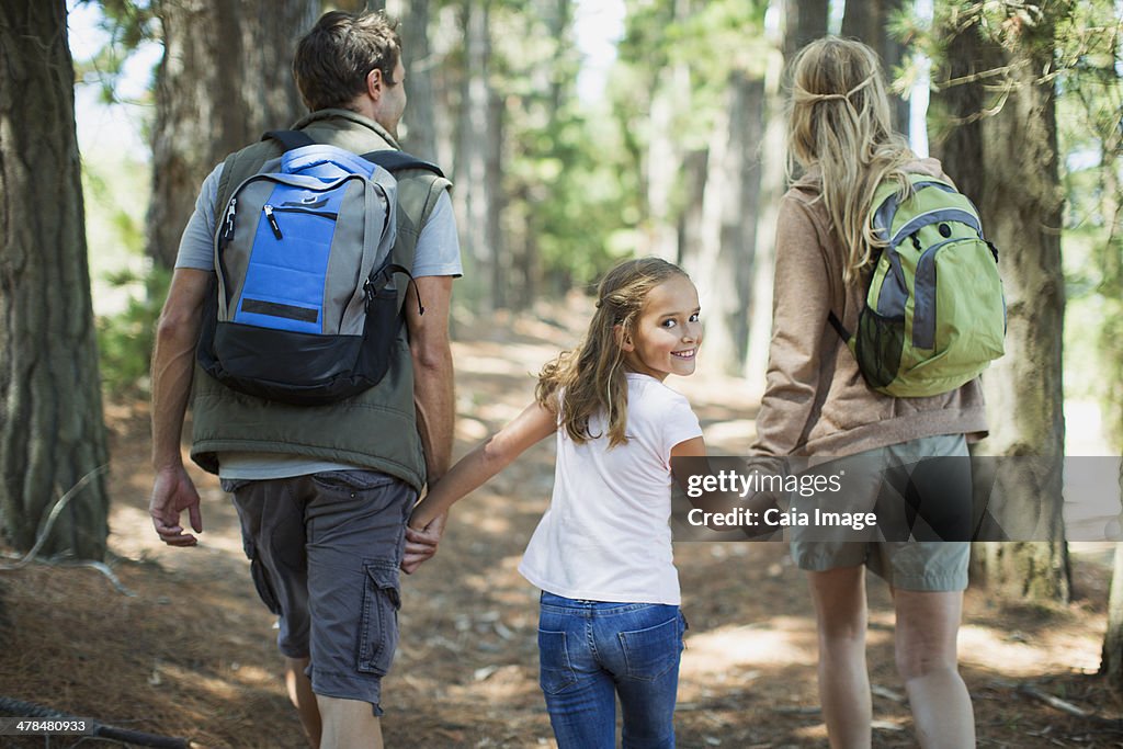 Smiling girl hiking with parents in woods