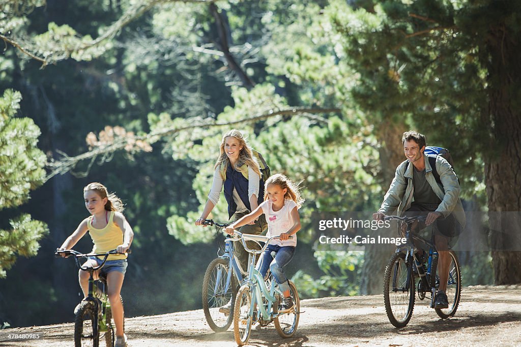 Smiling family bike riding in woods