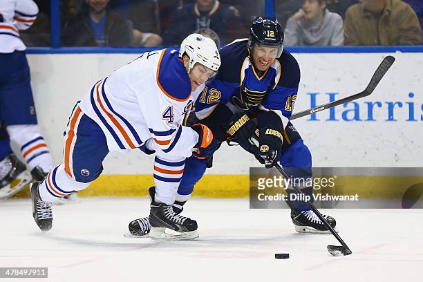 Taylor Hall of the Edmonton Oilers and Derek Roy of the St. Louis Blues chase down a loose puck at the Scottrade Center on March 13, 2014 in St....