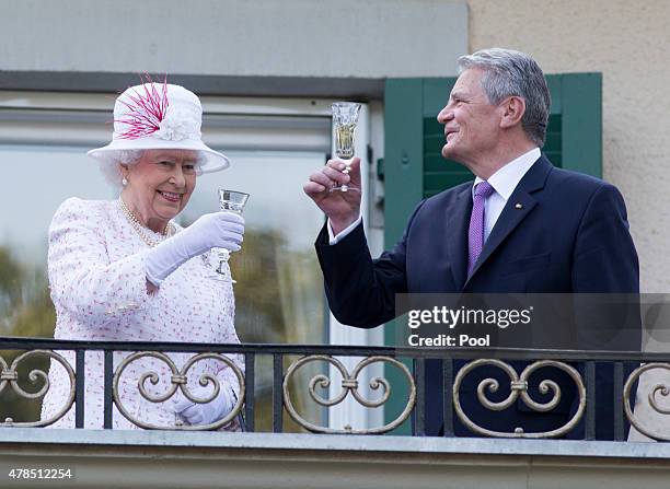 Queen Elizabeth II raises her glass with president of Germany Joachim Gauck as they attend a garden party at the British Embassy residence on day...