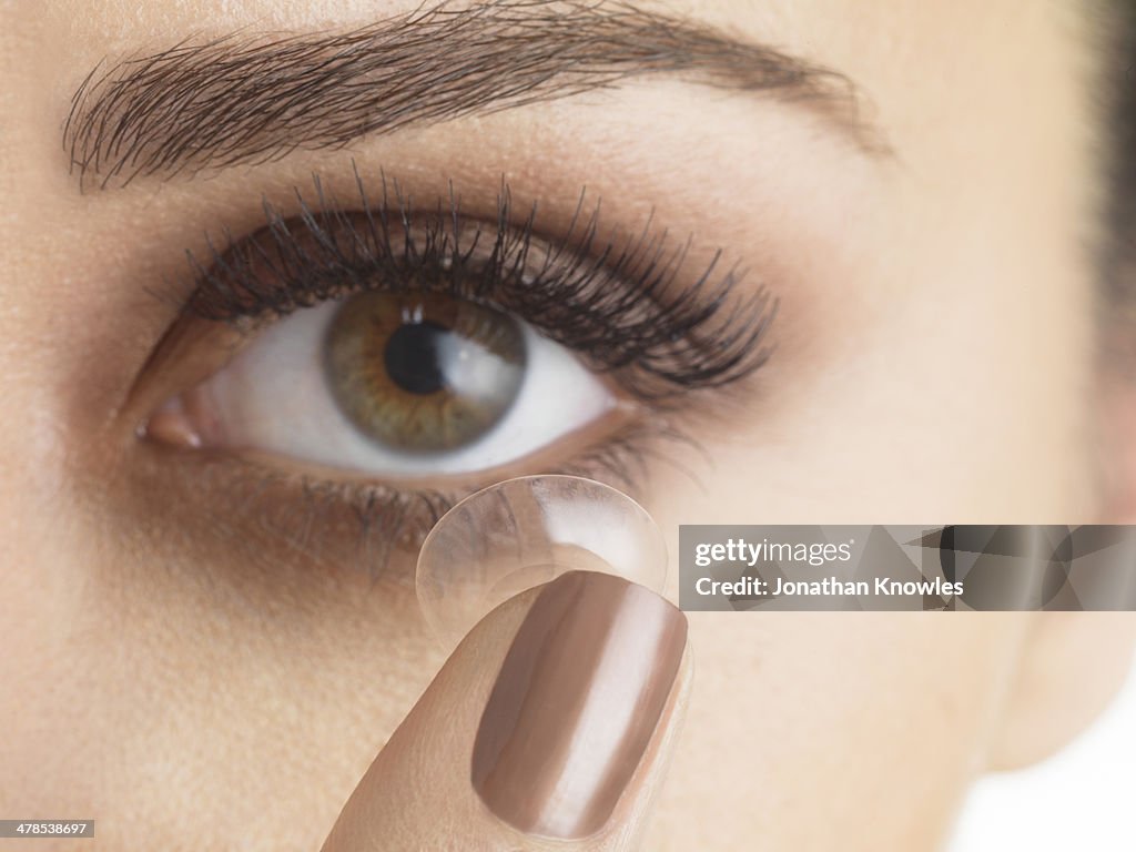 Female applying contact lenses,looking into camera