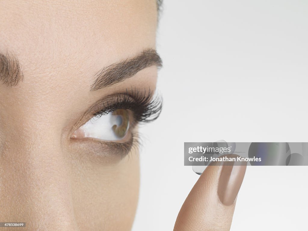 Female applying contact lenses, looking away
