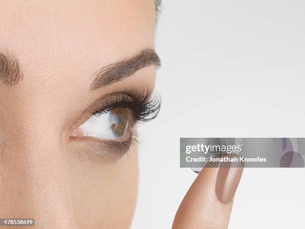 female applying contact lenses, looking away - lente de contacto imagens e fotografias de stock