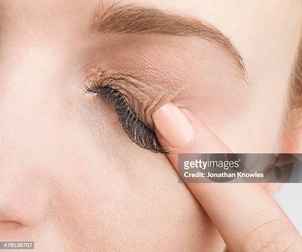 female  pressing closed eye with finger, close up - eyelid fotografías e imágenes de stock
