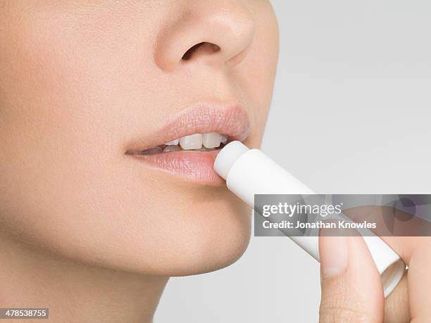 female applying lip balm, close up, side view - lèvres photos et images de collection