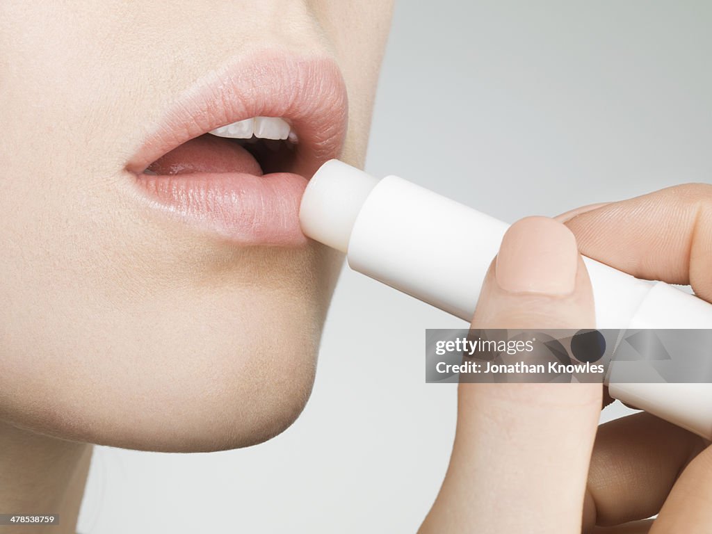 Female applying lip balm, close up, side view