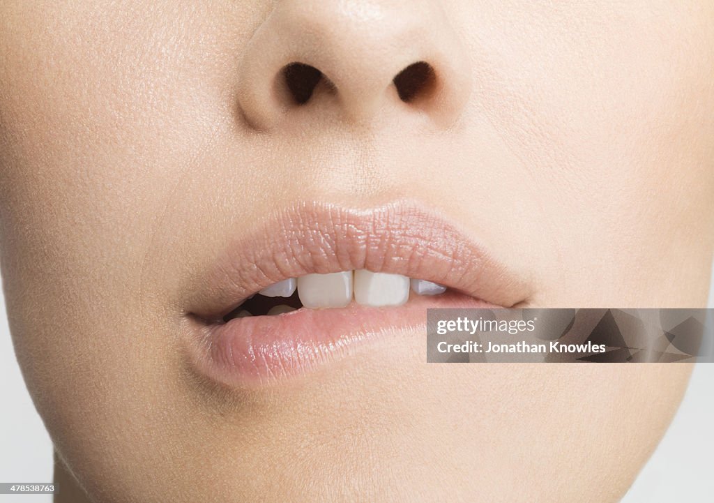 Detail of young woman biting lip, into camera