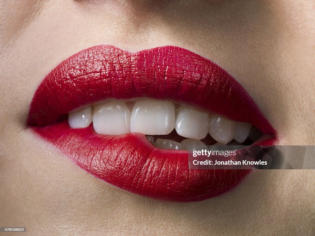 Female with red lipstick, biting lips, close up