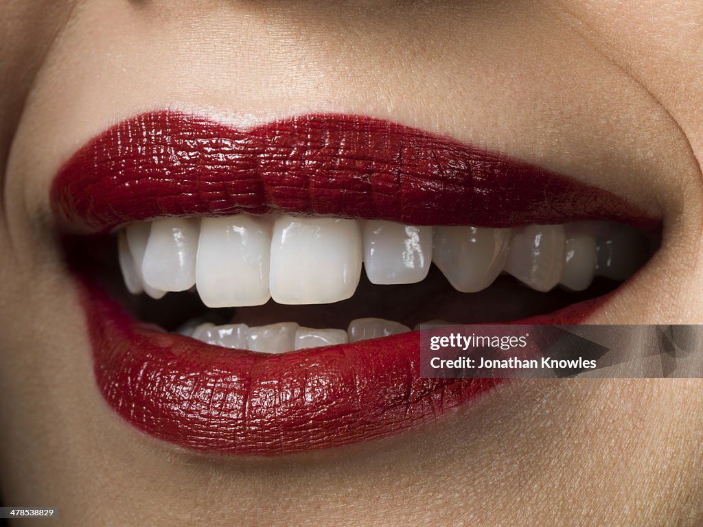 Female smiling with red lipstick on, perfect teeth