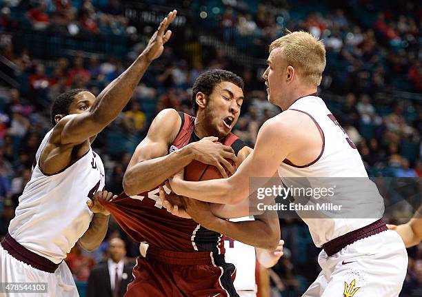 Josh Huestis of the Stanford Cardinal is fouled as he is tied up by Shaquielle McKissic and Jonathan Gilling of the Arizona State Sun Devils during a...