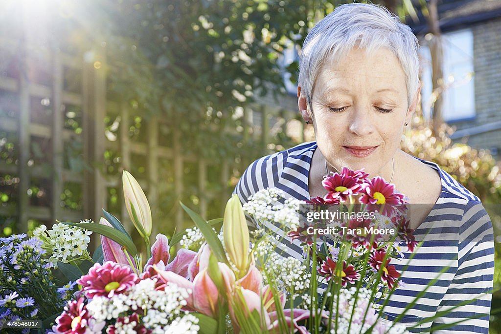 Mature woman smelling flowers in garden