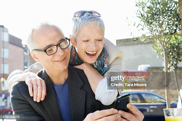 mature man and woman laughing looking at mobile - 50 59 years stock pictures, royalty-free photos & images