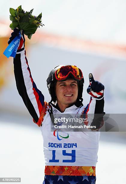 Evan Strong of the United States celebrates winning the gold medal during the flower ceremony for the Men's Para Snowboard Cross Standing on day...