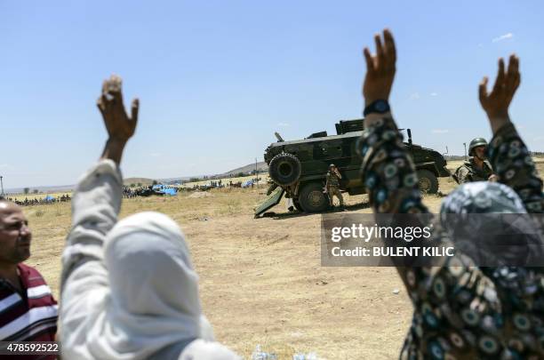 Relatives waves as Syrians gather on the Syrian side of the Turkey-Syrian border in Suruc in Turkey's Sanliurfa province, on June 26, 2015. At least...