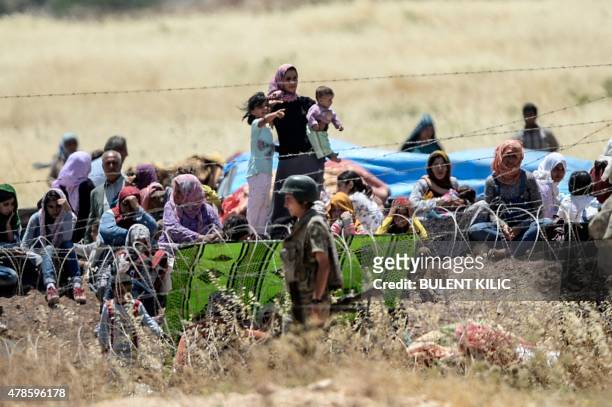 Picture taken from the Turkish side of the border in Suruc, Sanliurfa province, shows Turkish soldiers standing guard as Syrian Kurds wait behind the...