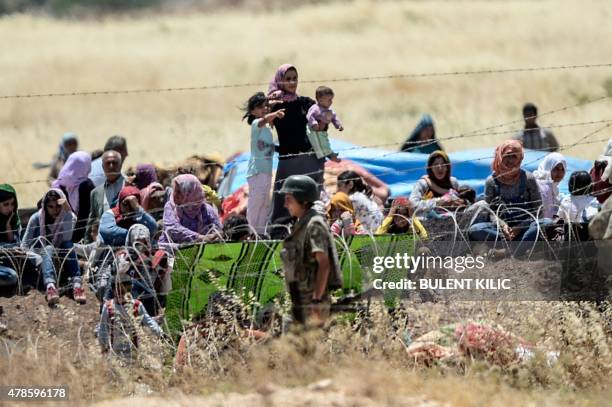 Picture taken from the Turkish side of the border in Suruc, Sanliurfa province, shows Turkish soldiers standing guard as Syrian Kurds wait behind the...