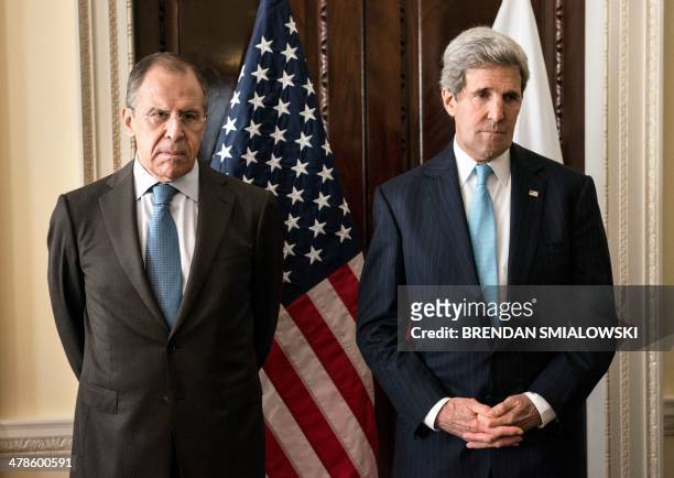 Russian Foreign Minister Sergey Lavrov and US Secretary of State John Kerry stand together before a meeting at Winfield House in London on March 14,...