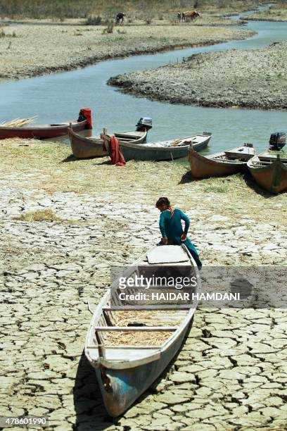 An Iraqi woman sits on a canoe stationed on dry, cracked earth in the Chibayish marshes near the southern Iraqi city of Nasiriyah on June 25, 2015....