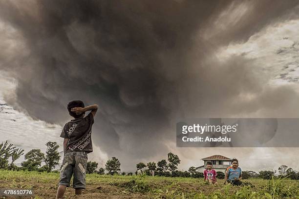 Children are seen as Mount Sinabung spews phyroclastic, matrial and ash volcanic from its crater in Karo, North Sumatra, Indonesia on June 26, 2015....
