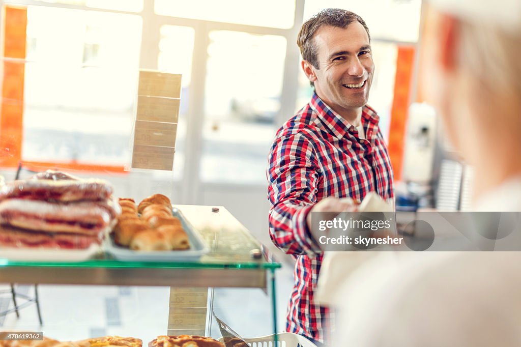 Happy man buying pastry in bakery.