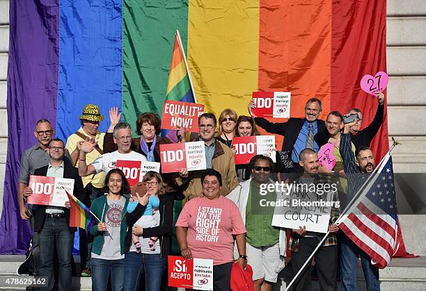 Supporters of same-sex marriage stand for a photograph in front of a rainbow flag displayed at City Hall after the U.S. Supreme Court ruling in San...