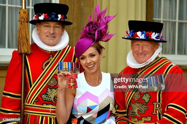Singer Katherine Jenkins holds her OBE with two Yeoman Warders during an Investiture Ceremony at Buckingham Palace on March 14, 2014 in London,...