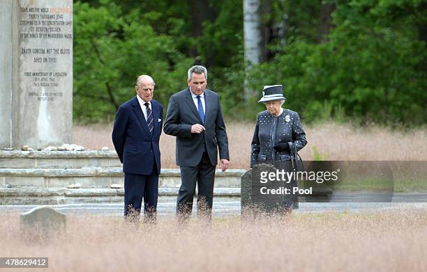 Queen Elizabeth II and Prince Philip, Duke of Edinburgh stand with Jens-Christian Wagner, director of the memorial, next to the grave of Anne Frank...